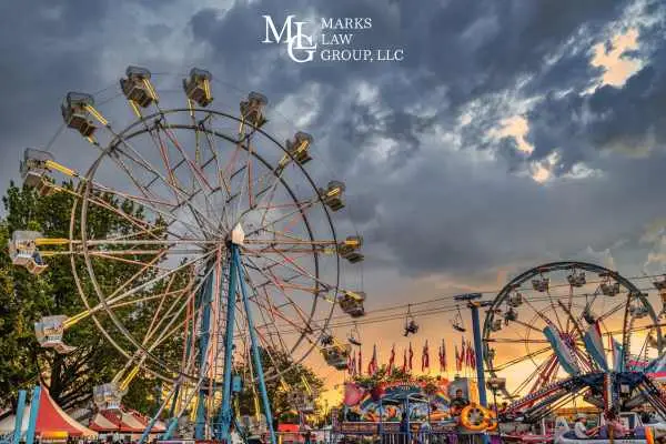 A Ferris wheel and fairground rides under a cloudy dusk sky