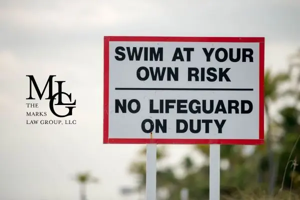 Roadside sign reading Swim at Your Own Risk, No Lifeguard on Duty