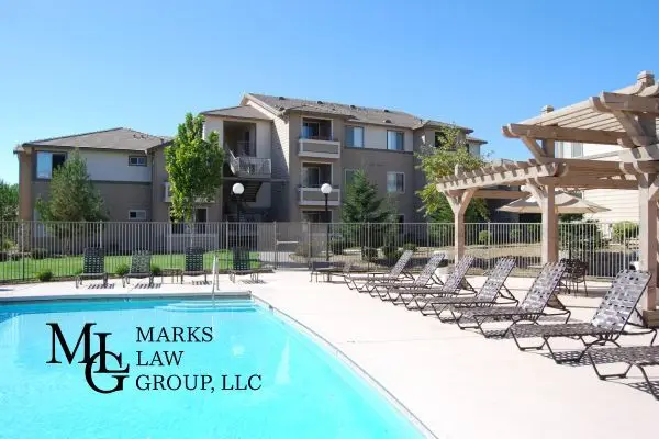 Apartment block behind a fenced outdoor pool lined with sun loungers