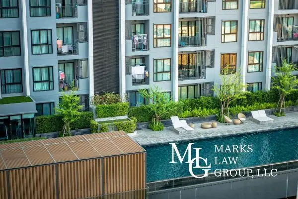 A swimming pool and sun loungers below the balconies of an apartment building