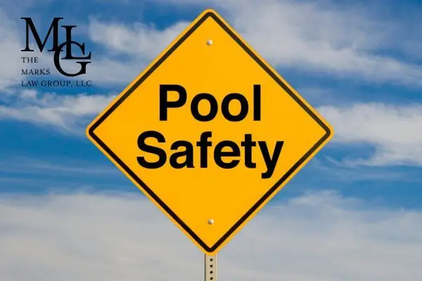A yellow diamond road sign reading Pool Safety against a blue sky