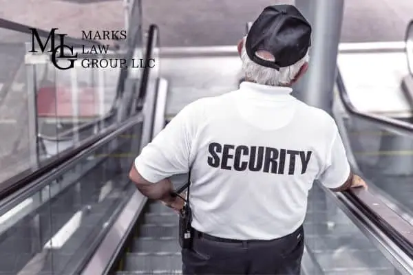 Security guard seen from behind riding an escalator, SECURITY printed on his shirt