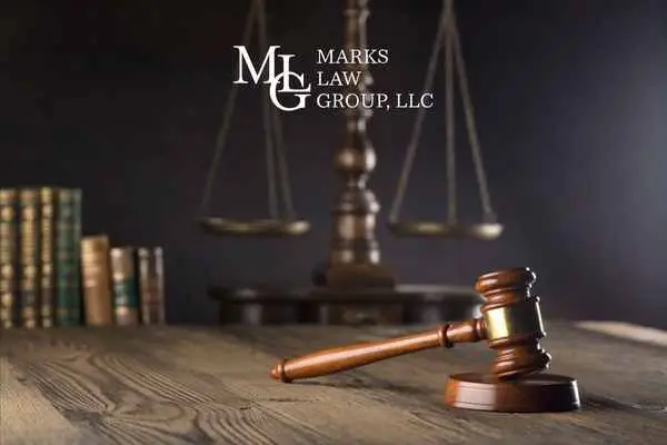 wooden gavel and law books before balance scales, watermark reading "Marks Law Group, LLC"