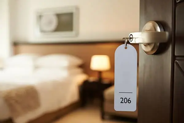 key with a tag numbered 206 in a hotel room door, bed behind