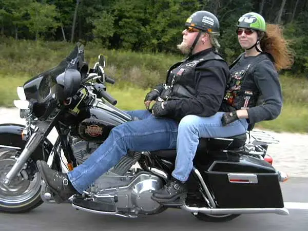 man and woman in helmets riding a large touring motorcycle on a road