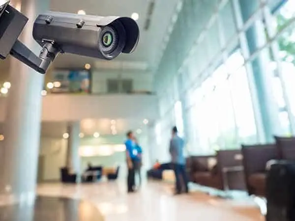 security camera mounted in a bright glass lobby with blurred people