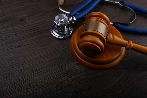 wooden gavel and blue stethoscope on a dark wood surface