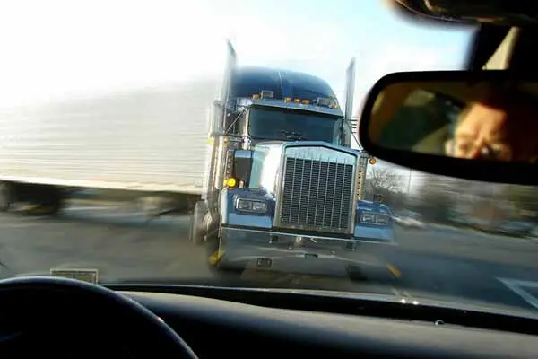 blue semi truck seen through a windshield from a car on the highway