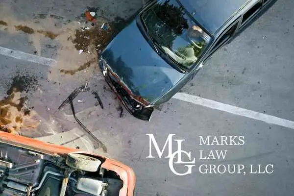 Overhead view of two wrecked cars with debris and fluid on the pavement