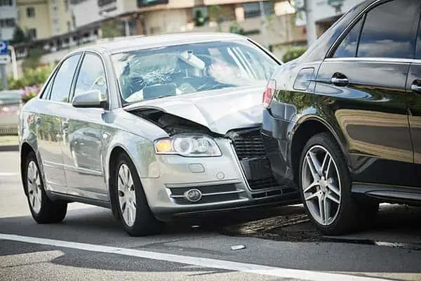 Silver sedan with a crushed front end rear-ending a black car on a street
