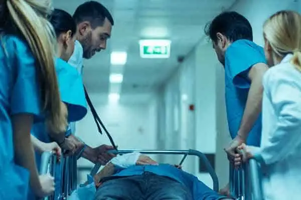medical team in scrubs rushing a patient on a gurney down a hospital corridor
