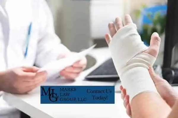 bandaged hand held up in a clinic, with a "Marks Law Group, LLC - Contact Us Today!" banner