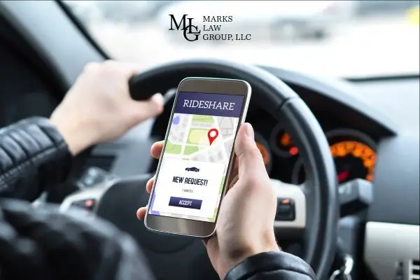 driver at the steering wheel holding a phone showing a rideshare ride request