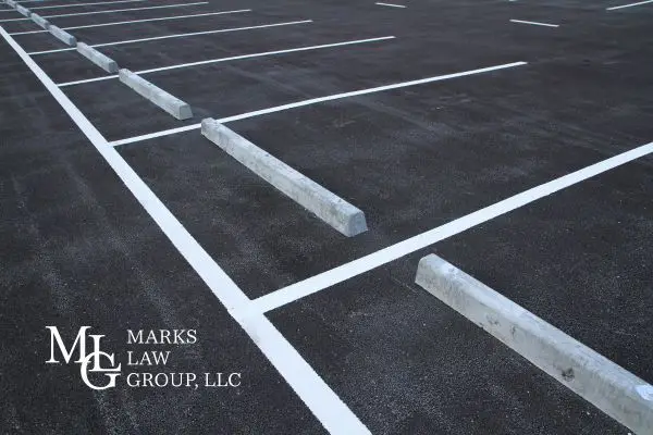 An empty asphalt parking lot with painted lines and concrete wheel stops