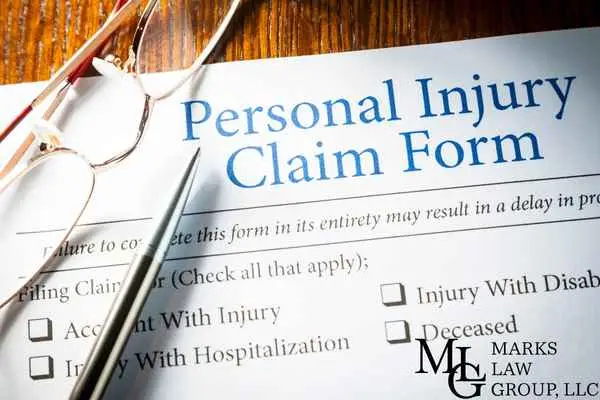 A Personal Injury Claim Form with checkbox options, glasses and a pen on top