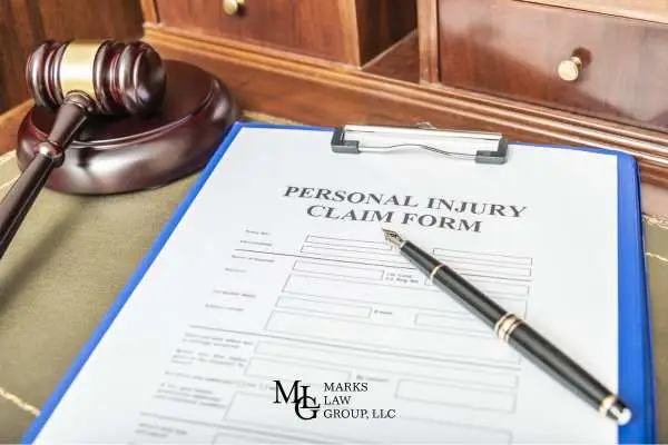A blank personal injury claim form on a clipboard with a fountain pen and a gavel