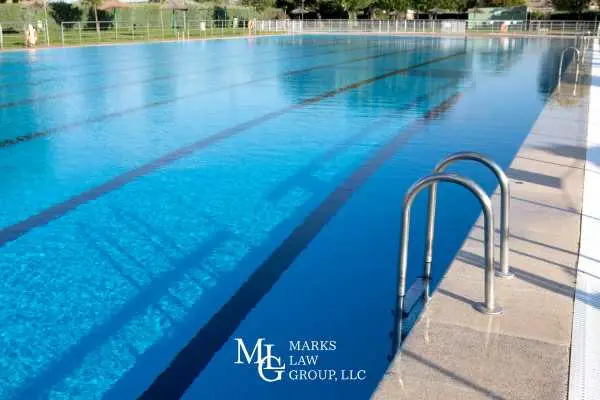 An empty outdoor swimming pool with lane lines and a metal ladder