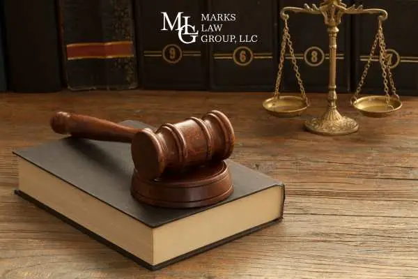 A gavel on a law book beside brass scales of justice
