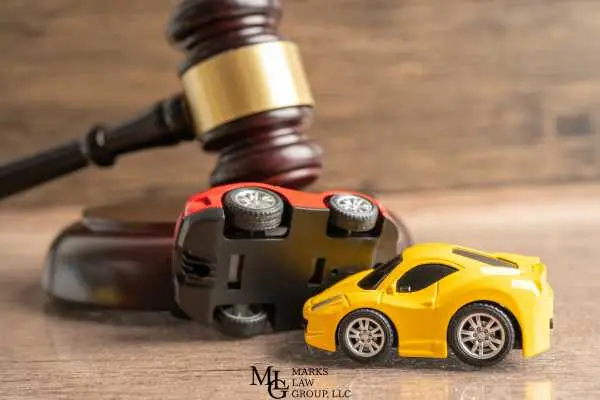 Two toy cars in a T-bone collision in front of a wooden gavel