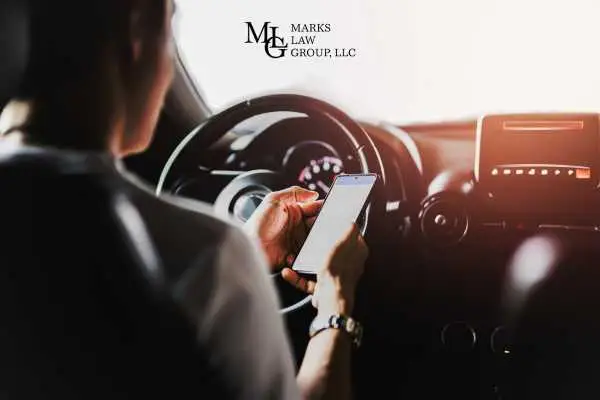 A driver holding a phone in one hand while steering with the other