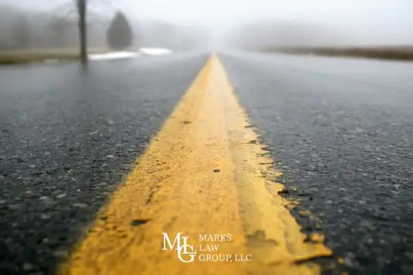 Yellow centre line on a wet foggy two-lane road seen from ground level