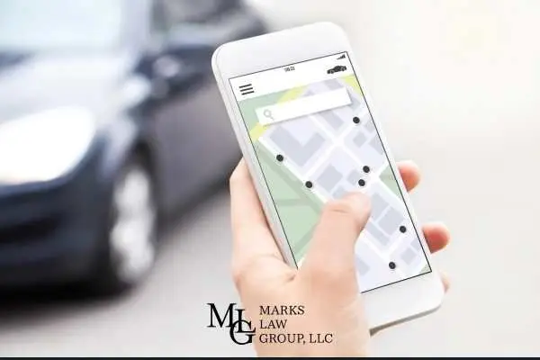 A hand holding a phone showing a ride-hailing map with nearby cars, sedan waiting behind
