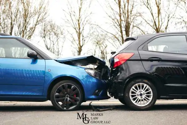 A blue car with its front crushed into the rear of a black hatchback