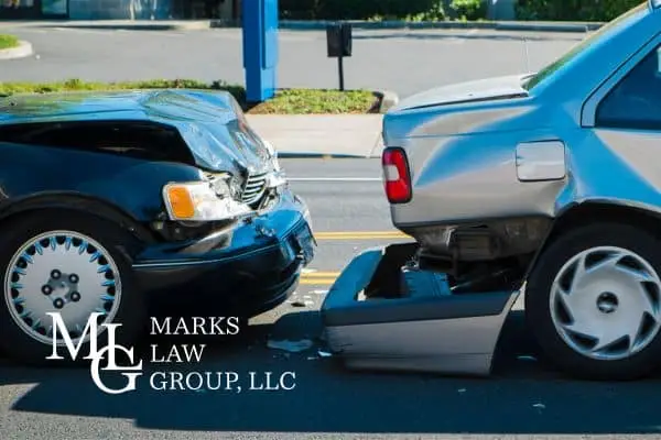 A dark car with a crumpled front end pushed into the rear bumper of a silver car