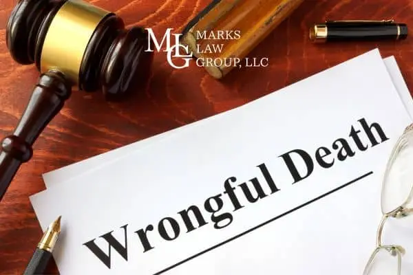 Sheets of paper headed "Wrongful Death" on a desk with a gavel, pen and glasses