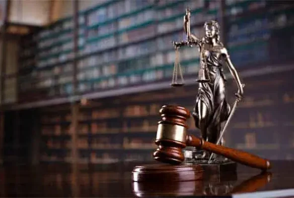 Bronze Lady Justice statue and a gavel on a desk before law books