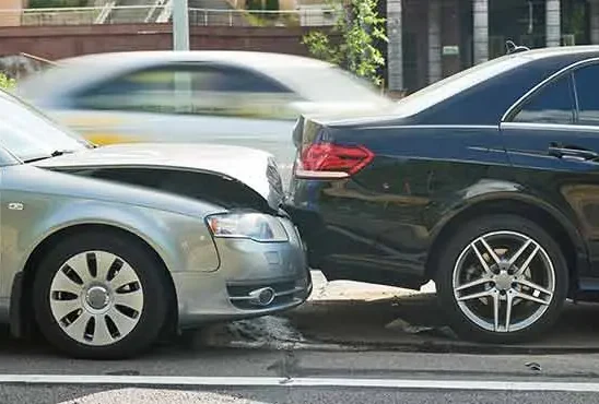 Grey car with a crushed front bumper pressed into a black sedan