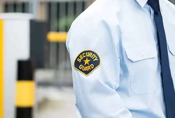 Close view of a security guard badge on a pale blue uniform shirt