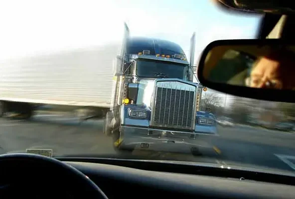 Oncoming semi truck seen through a car windscreen from the driver seat