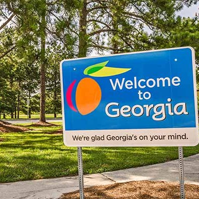 Roadside sign reading Welcome to Georgia among tall pine trees