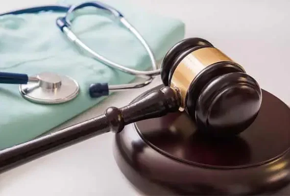 Wooden gavel resting beside a stethoscope on a surgical gown