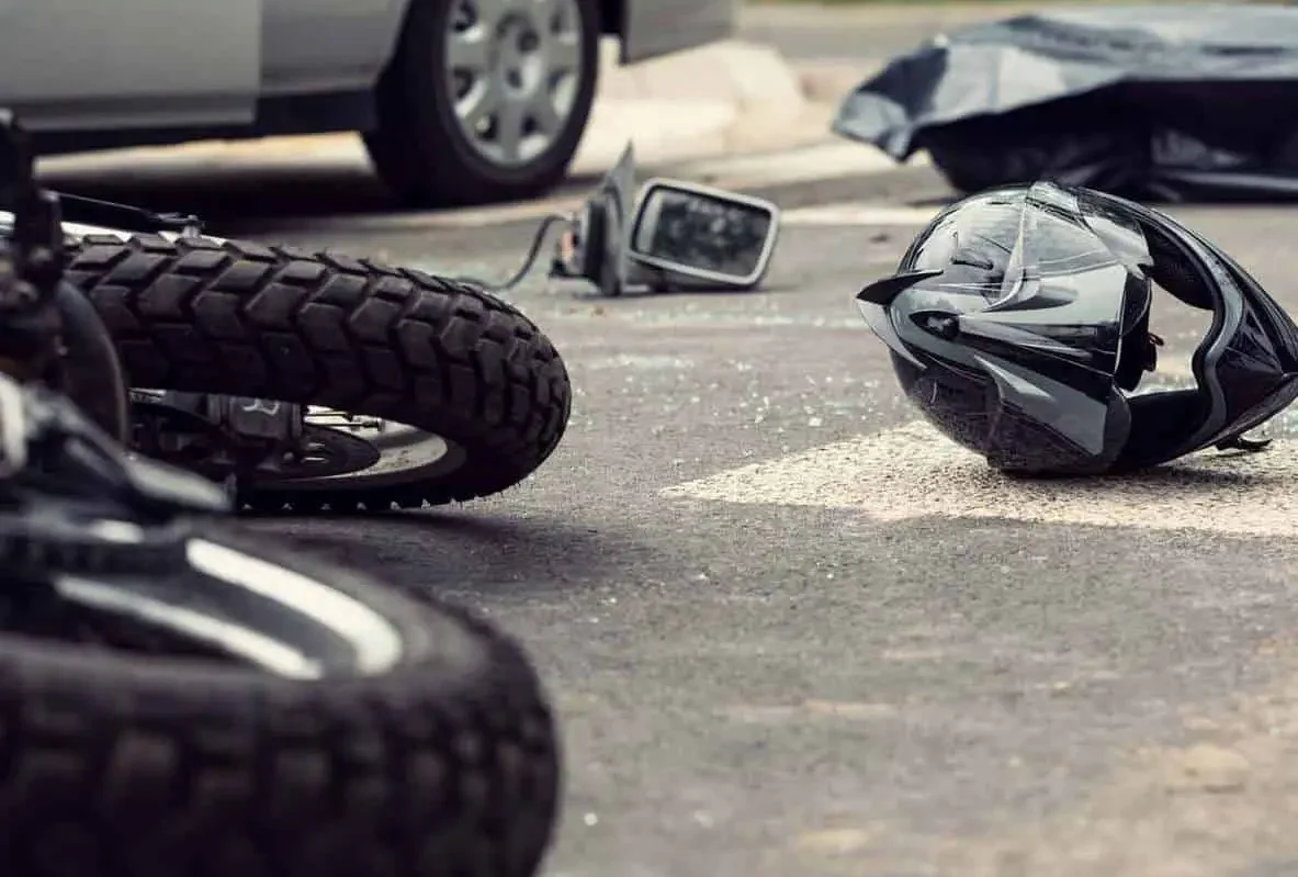 Fallen motorcycle and helmet on the road in front of a car