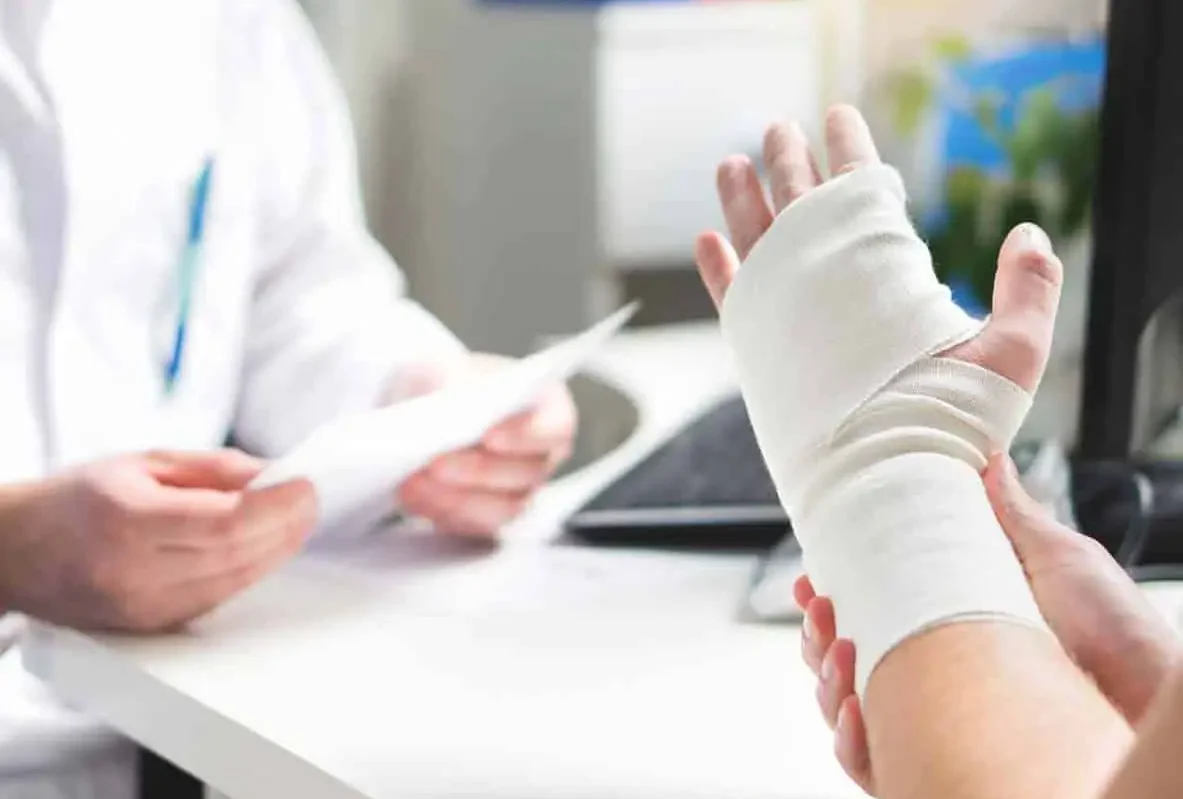 Patient showing a bandaged hand to a doctor across a desk