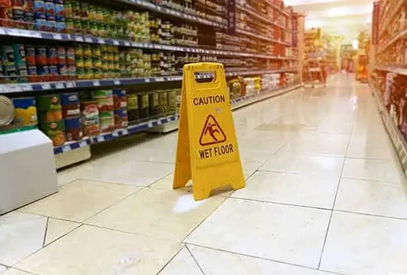 Yellow caution wet floor sign standing in a supermarket aisle