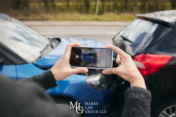 Person photographing the damage between two cars with a smartphone