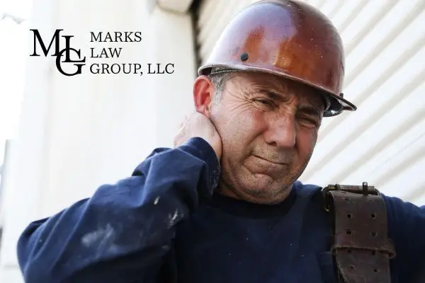 A construction worker in a hard hat gripping his neck in pain