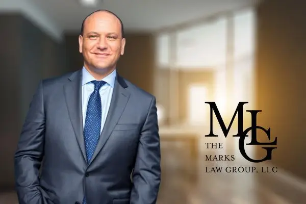 Man in a grey suit and blue tie standing in an office corridor