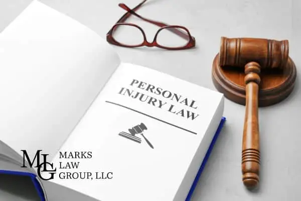 Open book titled Personal Injury Law next to a wooden gavel and glasses