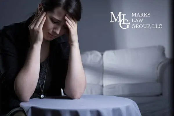 Woman sitting alone in a dim room holding her head in her hands