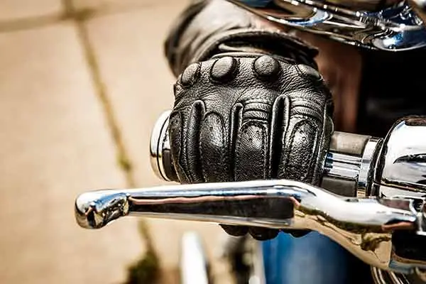 close-up of gloved hand gripping a chrome motorcycle brake lever
