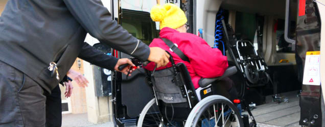 Driver assisting a passenger in a wheelchair into a non-emergency medical transport vehicle
