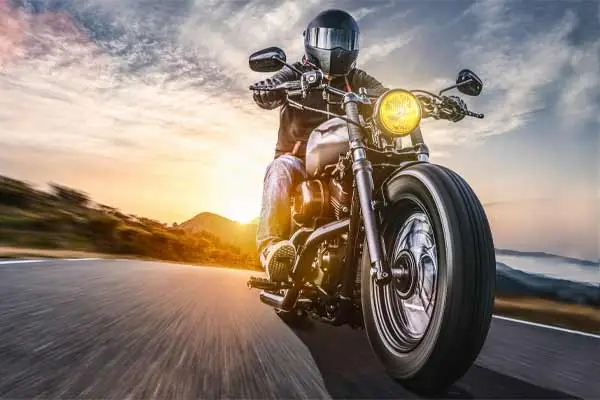 Motorcyclist riding a cruiser down an open road at sunset