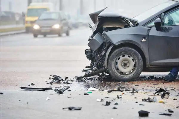 Car with a smashed front end and debris scattered across the road