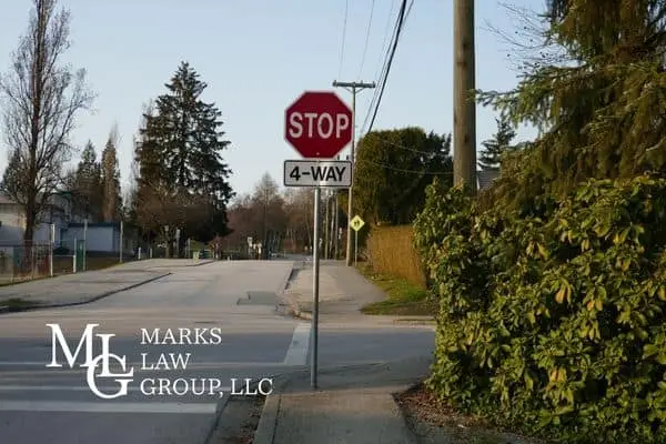 A red stop sign with a 4-WAY plate at a quiet residential intersection