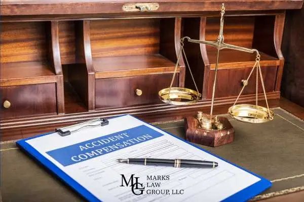 Clipboard with an Accident Compensation form beside brass scales of justice