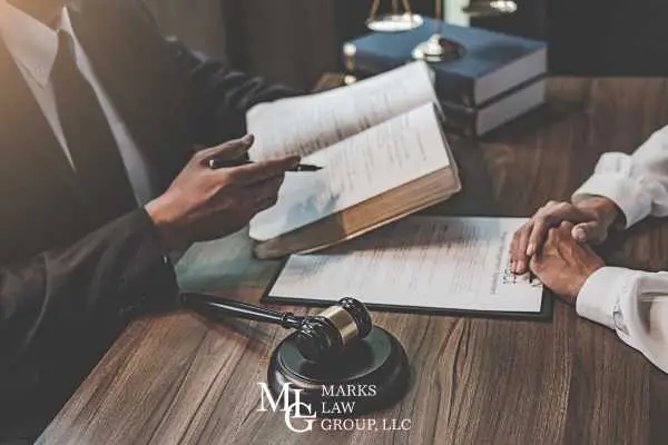 Two people across a desk with an open law book, documents and a gavel